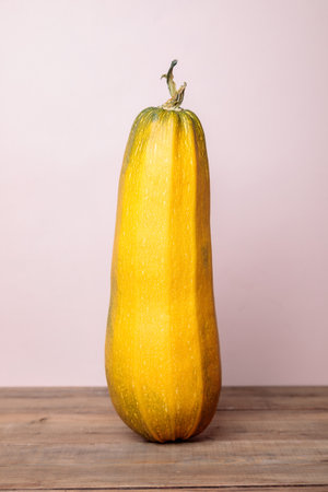 Yellow ripe zucchini with lemon on a pink background. Autumn concept. Close-up.の写真素材