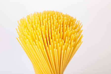 An upright bunch, a bunch of raw spaghetti tied with rope. Bundle on a white background. Italian food concept.の写真素材