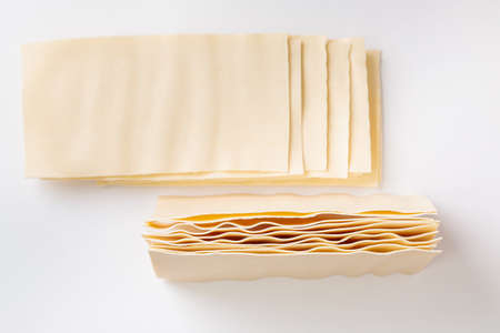 Raw lasagna. Dry dough sheets for lasagna on a white background. Italian food.の写真素材