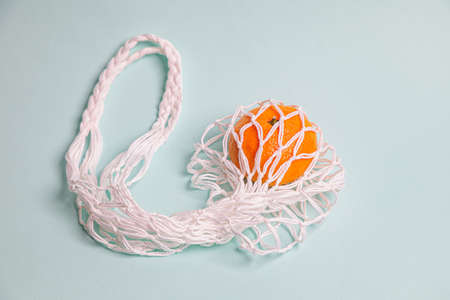 Eco-friendly mesh with tangerines on a blue background. New Year's celebration.