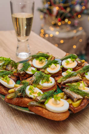 Toasted bread with sprats, eggs and herbs. Traditional Russian food for the New Year's table.の写真素材