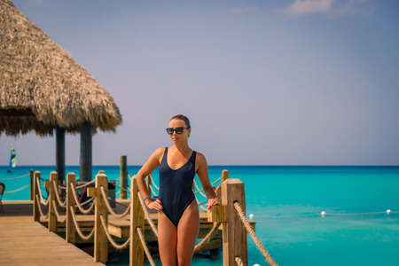 A young girl in a bathing suit stands on a wooden pier by the sea. Posing for the camera. High quality photoの写真素材