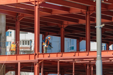A male builder works with a hand tool on a frame of iron beams. Construction. Moscow Russia April 14, 2022のeditorial素材