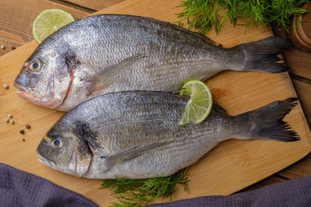 Raw peeled dorado fish with cooking ingredients. Fresh fish on a wooden background