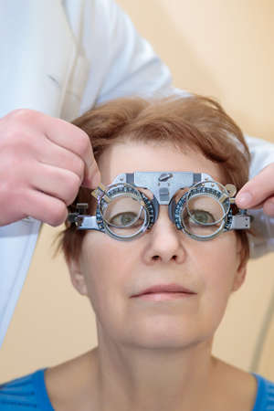 A male optometrist checks the eyesight of an adult woman with a trial frame.の写真素材