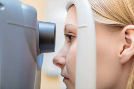 A young girl at the reception at the ophthalmologist checks her eyesight on a special apparatus....