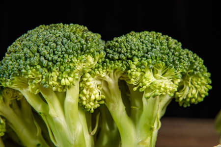 Raw green broccoli florets on a wooden board with ingredients. close-up.の写真素材