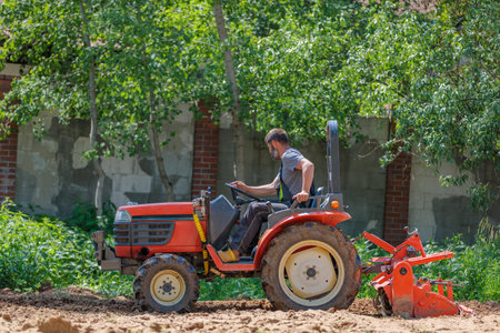 A man on a mini-excavator levels a piece of land, loosens the soilの写真素材