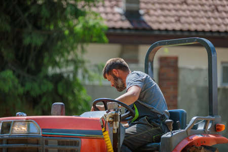 A man on a mini-excavator levels a piece of land, loosens the soilの写真素材