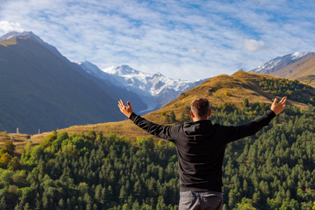 A man stands on top of a mountain with his arms outstretchedの写真素材