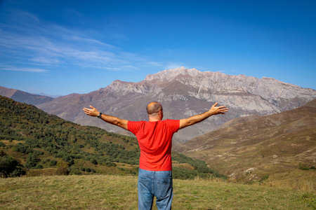 A man stands on top of a mountain with his arms outstretchedの写真素材