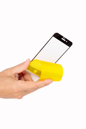 The hand holds a protective screen for a mobile phone. white background. close-up