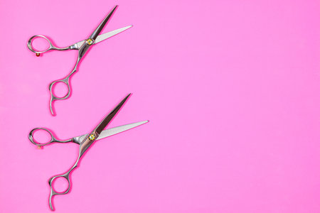 A set of hairdressing tools of two scissors on a pink backgroundの写真素材