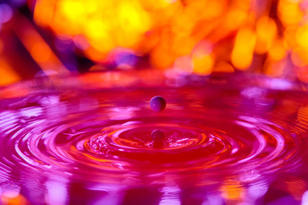 A drop falls into a dense liquid with a red background. abstract colorful backgroundの写真素材