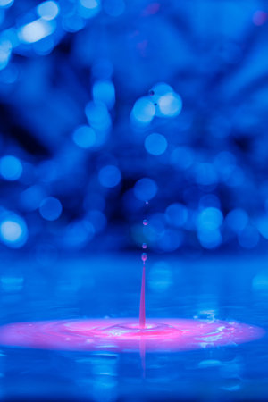 A drop falls into a thick liquid with a blue-pink background. abstract colorful background