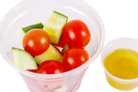 Salad of cucumbers, cherry tomatoes, peppers and dressing on a white background. Side view. Isolate.の写真素材