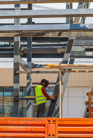 A man-welder fastens iron girders with a welding machine. Construction of the station