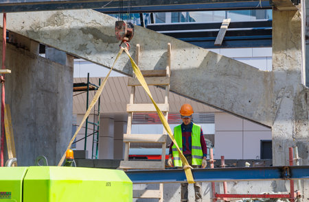 Moscow, Russia. June 30, 2023. A male construction worker accepts an iron beam on a craneのeditorial素材