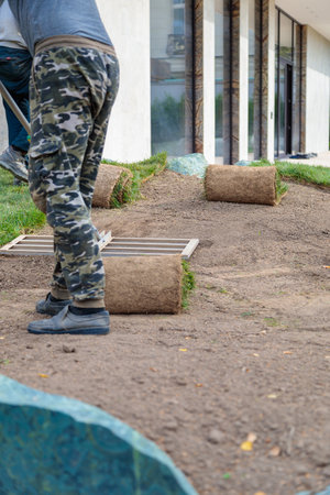 Man laying rolls of grass lawn. Landscaping conceptの写真素材