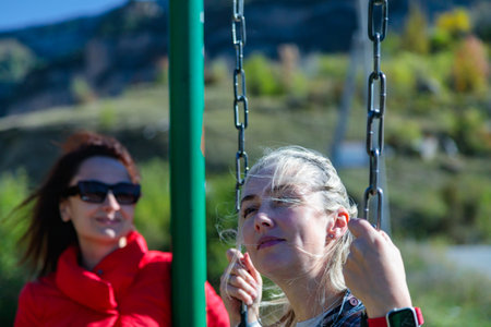 Girl enjoying swinging on a swing surrounded by majestic mountains in a beautiful natural landscapeの写真素材