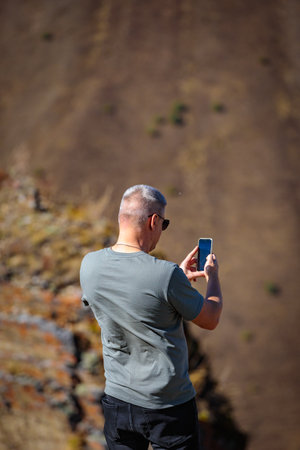 Man taking pictures of the beauty of the mountainous area using his mobile phoneの写真素材