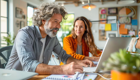 A man and woman at a table, smiling and looking at a laptop screen in a building, enjoying leisure time togetherの素材
