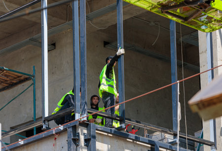 Male construction workers are installing the iron frame for the glazing of the buildingのeditorial素材