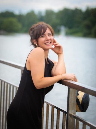 Beautiful woman on the bridge by the pond with a hatの写真素材