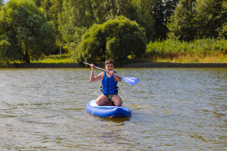 An energetic guy on a SUP board, enjoying riding the waves on a sunny day.の写真素材