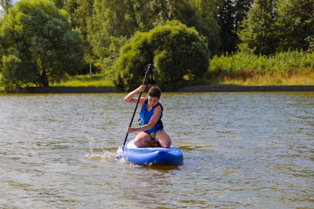 An energetic guy on a SUP board, enjoying riding the waves on a sunny day.の写真素材