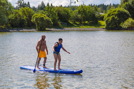 Father lovingly shows his son his SUP surfing skills by floating on the wavesの写真素材