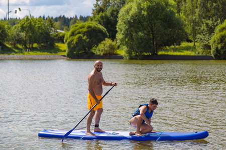 Family study: the father leads his son on the waves on a SUP board.の写真素材