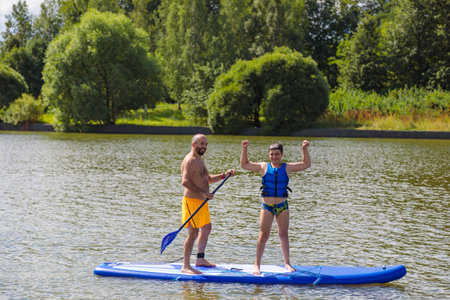 Family study: the father leads his son on the waves on a SUP board.の写真素材