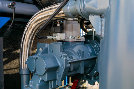 Close-up of a screw compressor with a flexible metal hose, showcasing its components and industrial...