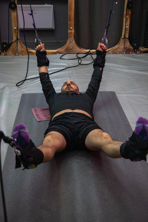 Male athlete performing a suspension training exercise, working on core strength and stability
