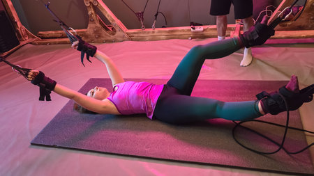 Young woman performing anti gravity yoga exercise with suspension strapsの写真素材
