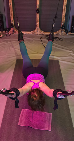 Woman doing back exercise with suspension straps in gymの写真素材