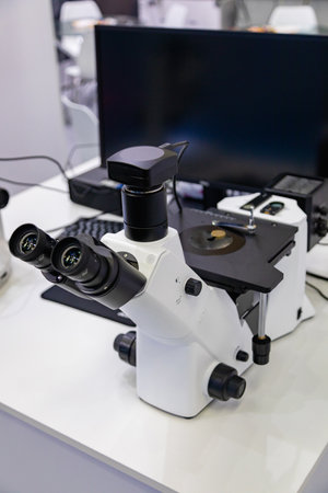 Modern digital microscope stands on laboratory table with computer displaying research dataの写真素材