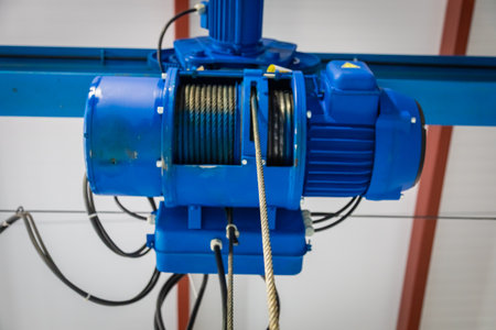 Close up of a powerful blue electric hoist, showcasing its intricate mechanism and strong steel...