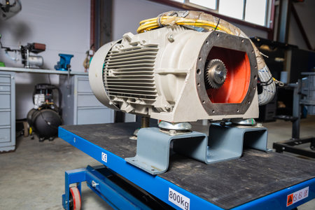 Electric motor sits securely on a blue cart, awaiting servicing or repair in a bustling workshop environmentの写真素材
