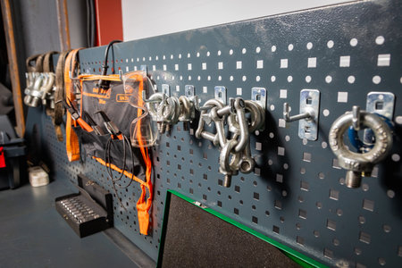 Metal shackles, lifting slings, and safety goggles hanging on a pegboard in a well organized workshop, showcasing workplace safety and efficiencyの写真素材