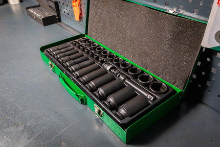Set of impact sockets and extensions neatly organized in a green metal toolbox, resting on a...