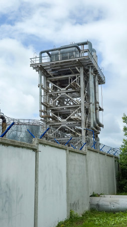 Industrial plant standing tall behind concrete wall with barbed wireの写真素材