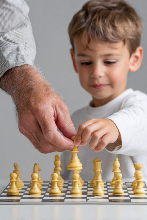 Grandfather and grandson moving chess pieces on a chessboard, learning and having fun togetherの素材