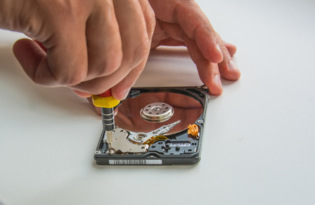 Two man hands fixing hard disc using screwdriver. Extreme close-upの写真素材