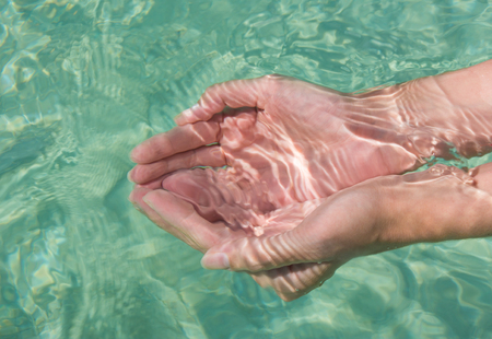Clear blue water in woman's hands. Turquoise water background