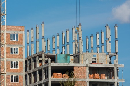 The construction of multi-storey building under blue sky. Apartment house site. Concrete poles as the frame of a multi-storey building on the blue backgroundの写真素材