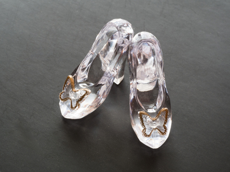 Clear glass pair of shoes for doll isolated on black backgroundの写真素材