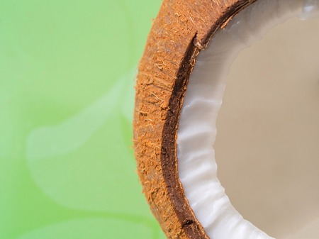 Coconut half on green background, copy space, texture, close up