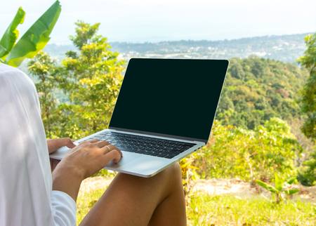 Close up shot of woman with laptop with copy space at tropical viewpoint. Working, studying outside. Work in natureの写真素材